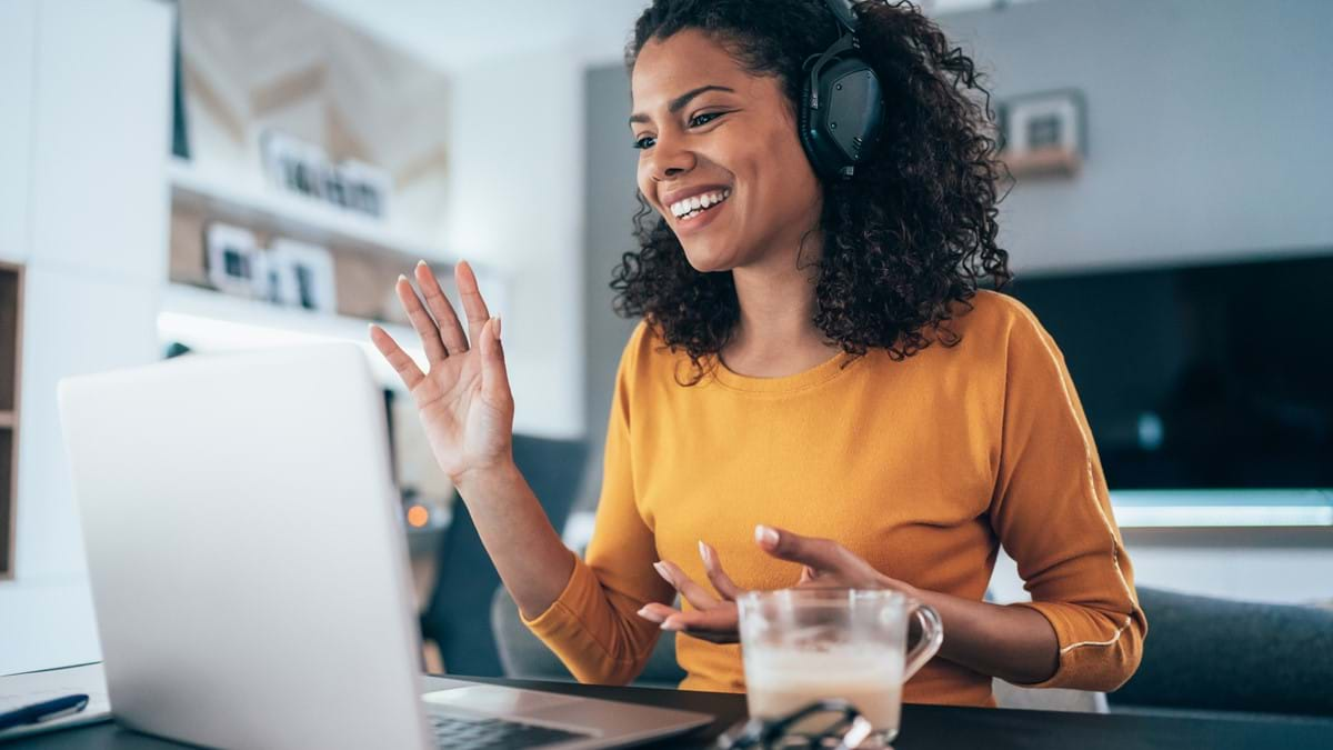 Woman sitting in front of laptop waving